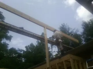 Carpenter setting a ridge beam over a new addition frame — Ice Dam Removal by Roofing Brothers in Elrod