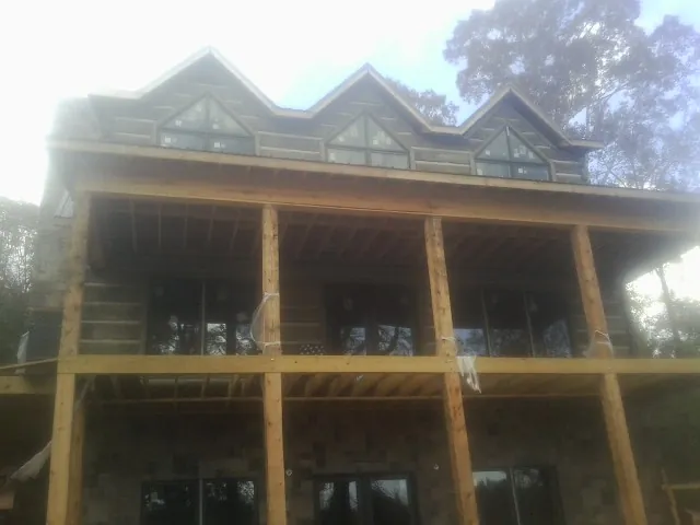 Dormers and porch framing on a large log home under construction — Roof Coating work by our crew in Elrod