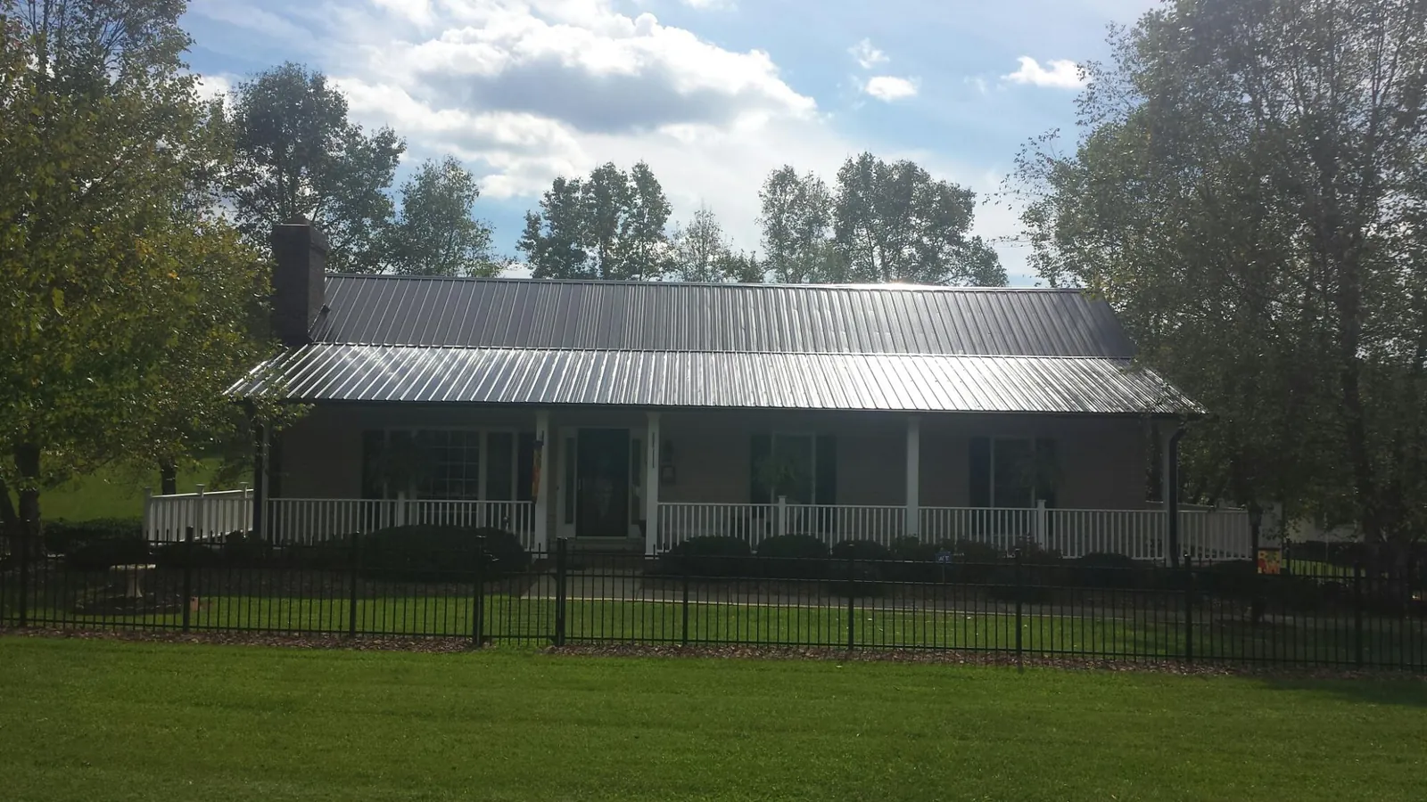 Gray metal roof on a brick ranch with a full width front porch — Gutter Guard Installation work by our crew in Elrod