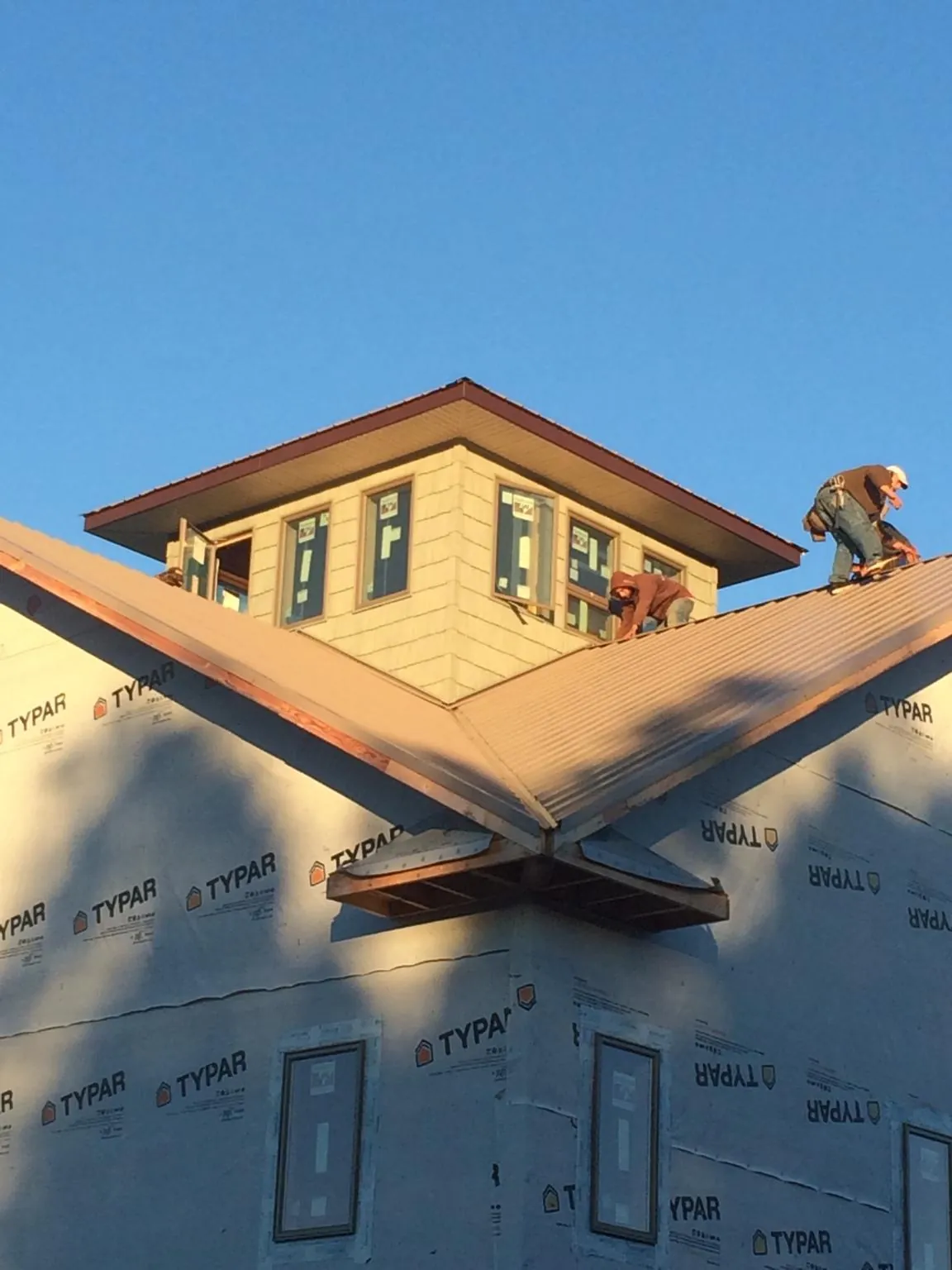 Roofers working around a rooftop cupola on a new metal roof at sunset — Roof Waterproofing in Elrod by Roofing Brothers
